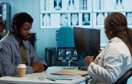 African american young man and specialist review ct scans and x rays, discussing about treatment after established diagnosis. Medic practitioner does scan interpretation, expertise. Camera A.